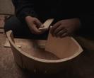 A man's hands assemble a wooden bucket on a wooden floor.