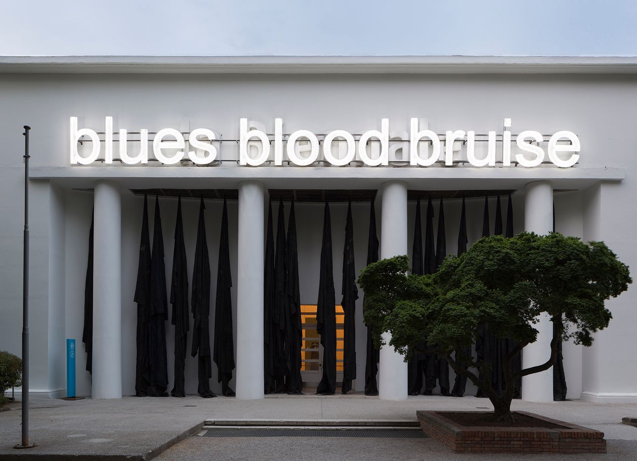 Building with the words "blues blood bruise" illuminated on its facade
