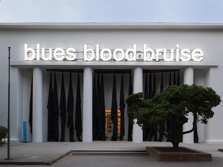 Building with the words "blues blood bruise" illuminated on its facade
