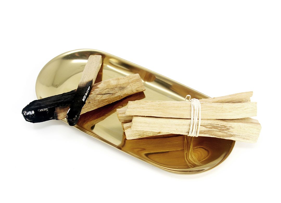 Two bundles of palo santo sticks in a gold tray.