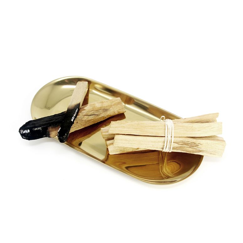Two bundles of palo santo sticks in a gold tray.
