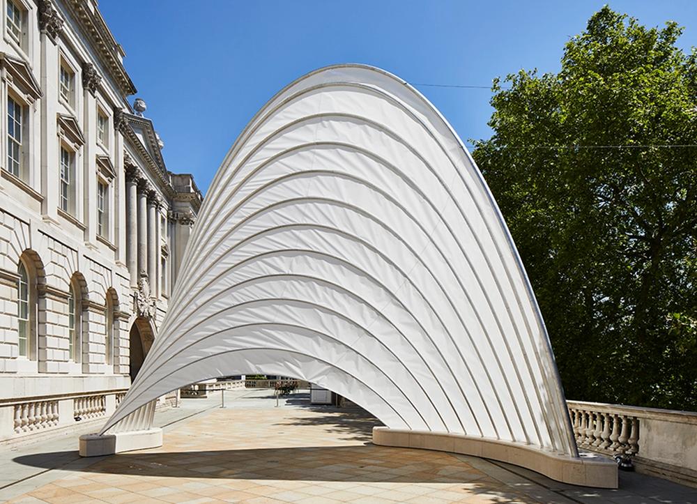 An arched white structure on a terrace 