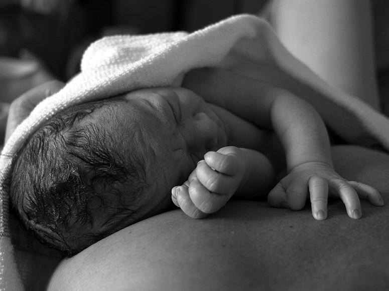 A photo of a newborn on its mother's chest.