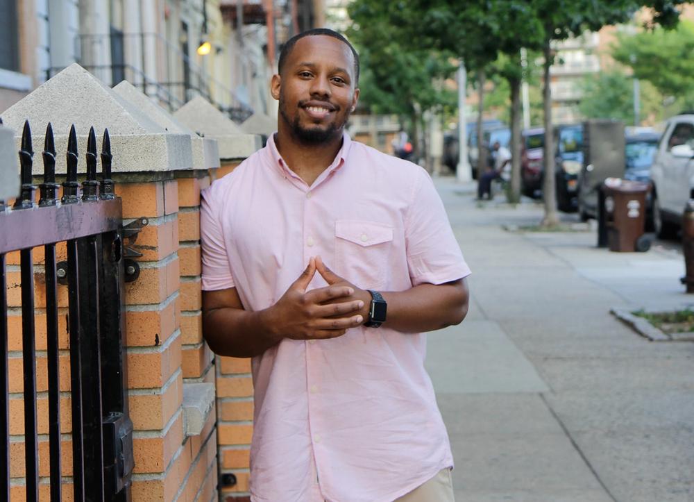 Eat Okra co-founder Anthony Edwards in a pink shirt on the sidewalk.