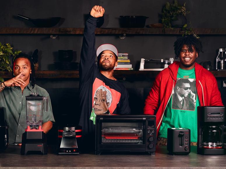 Ghetto Gastro members behind their black and red blender, toasters, coffee maker, and air fryer.