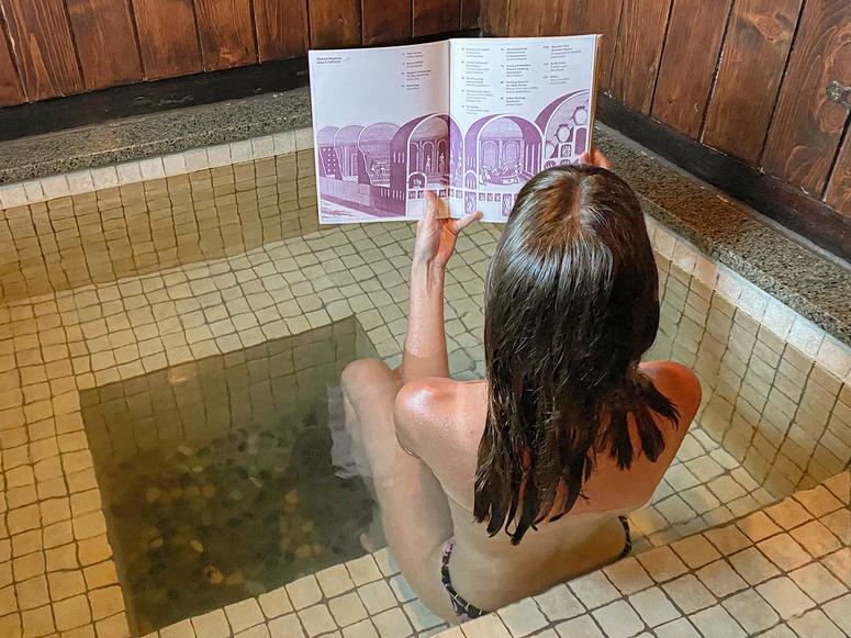 A woman reads a magazine in a hot tub wearing a swimsuit