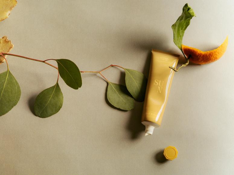 3rd Ritual's Sun balm in a yellow squeeze tube, on top of a leaf and orange rind.