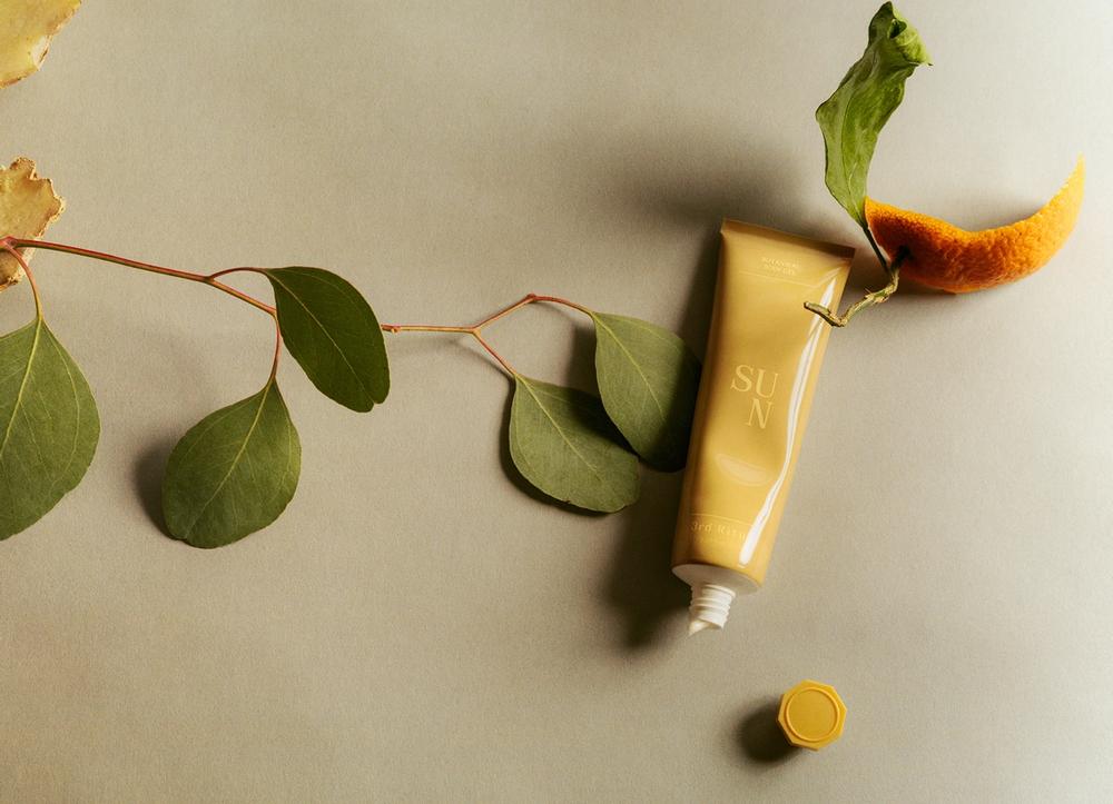 3rd Ritual's Sun balm in a yellow squeeze tube, on top of a leaf and orange rind.