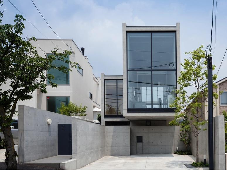 A concrete home with a large window flanked by two trees