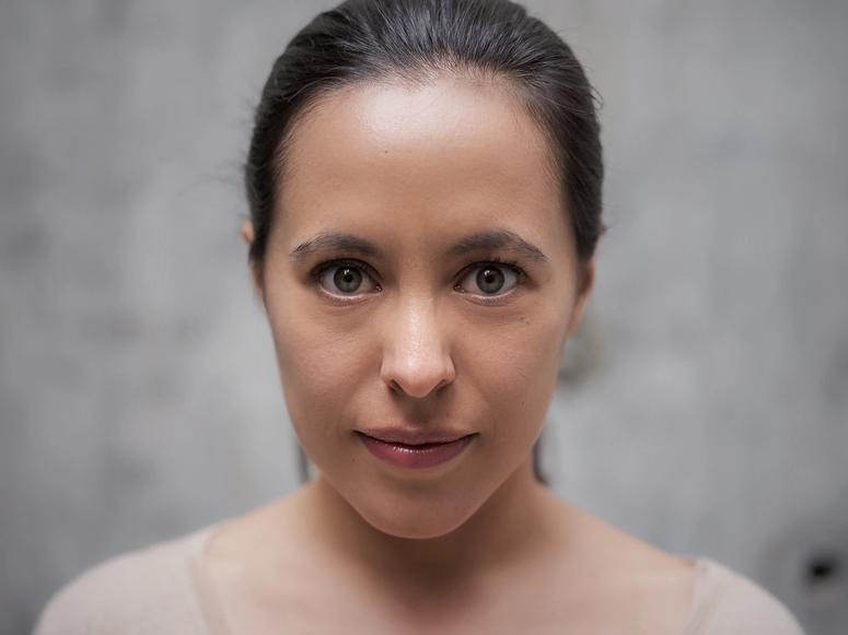 Olivia Jezler gazing into the camera on a gray background.