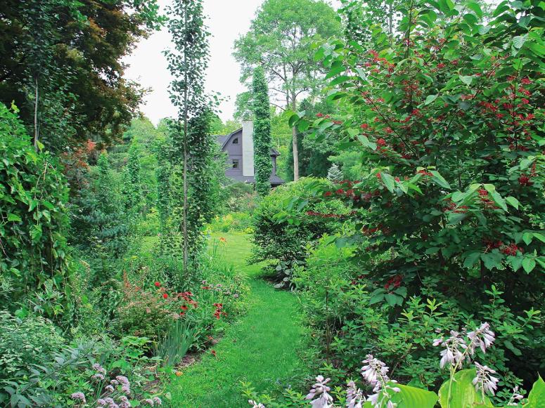 A garden with many different flowers and a cottage in the background.