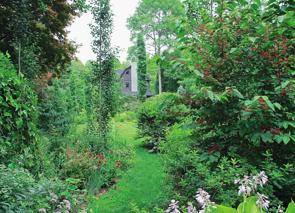 A garden with many different flowers and a cottage in the background.