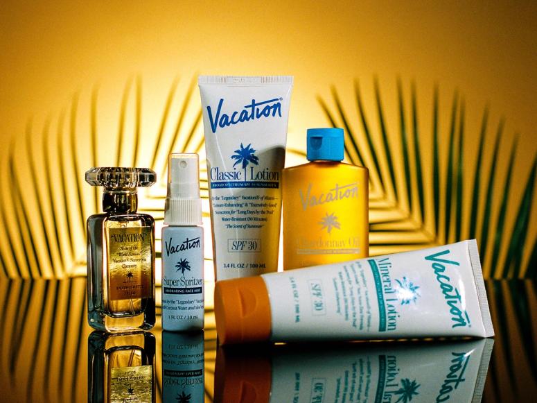 Tubes of sunscreen and a perfume shot in front of palm leaf branches