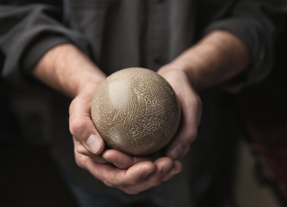 Two hands cupping a dorodango mud ball.