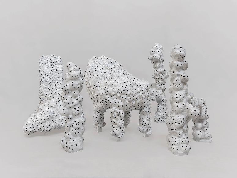 A bumpy white chair filled with black holes.