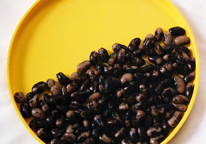 A yellow plate half filled with black beans.