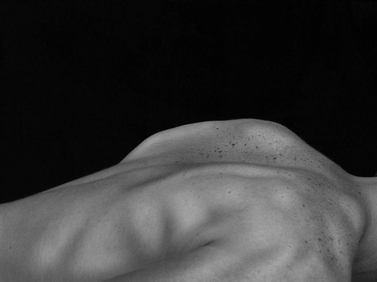 A person's bare back against a black background.