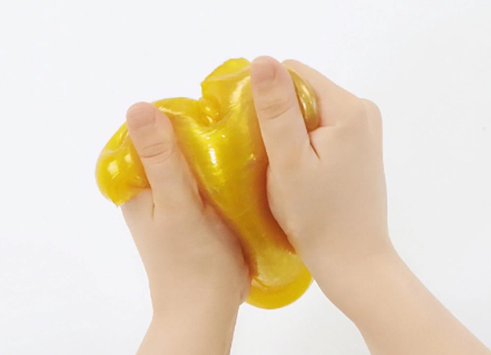 Two hands playing with yellow slime.