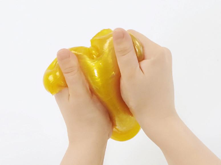 Two hands playing with yellow slime.