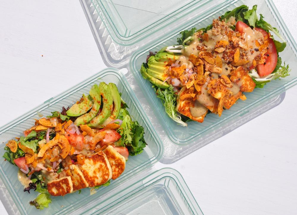 Two Case containers with multicolored salads inside.