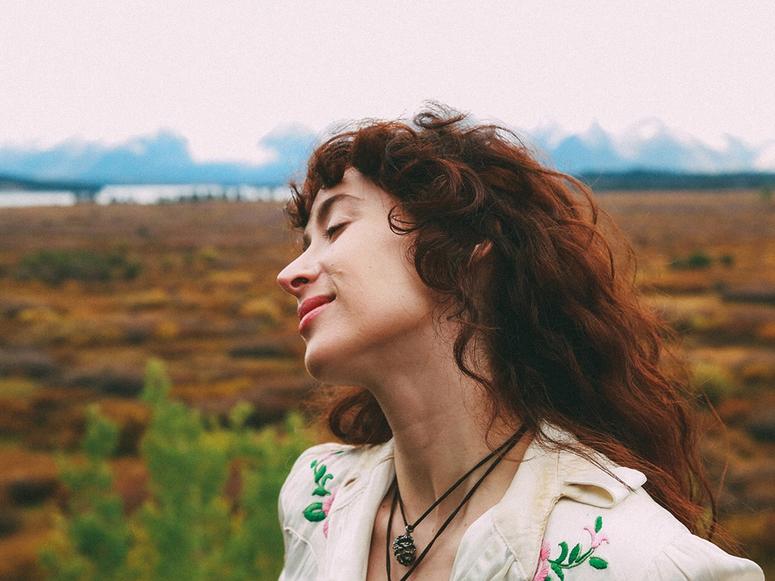 Ayanna Young in an embroidered shirt, smiling in the wilderness.
