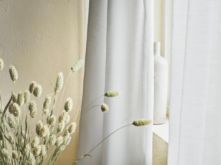 White curtains in front of stalks of wheat.