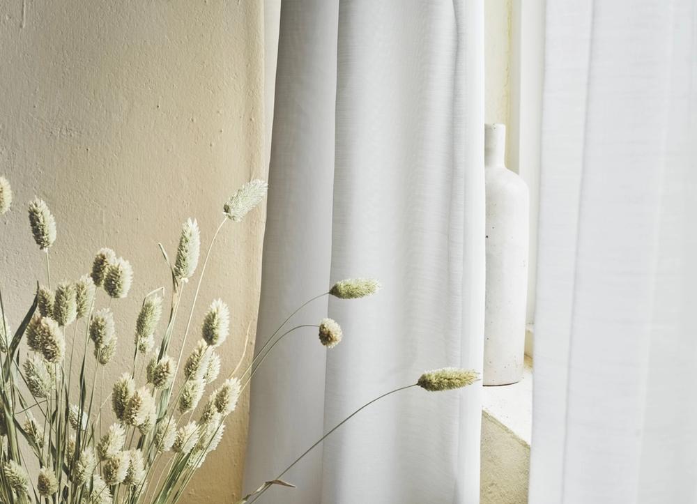 White curtains in front of stalks of wheat.