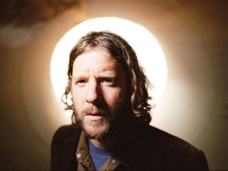 Billy Martin standing before a bright, white light, looking into the camera.