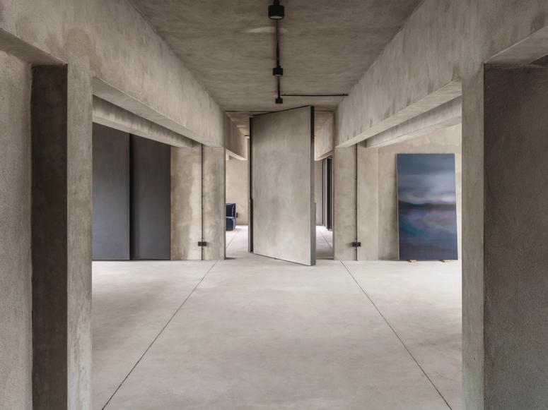 A view into an empty concrete interior with a revolving door at its center