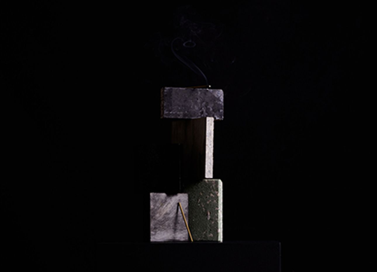A stick of incense balanced with four pieces of stone
