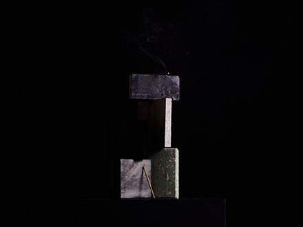 A stick of incense balanced with four pieces of stone