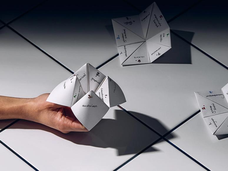 A hand holding a paper origami fortune teller