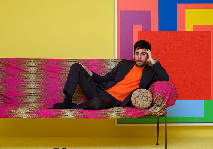 Omar Sosa reclining on a brightly colored couch in his brightly colored Friedman Benda show.