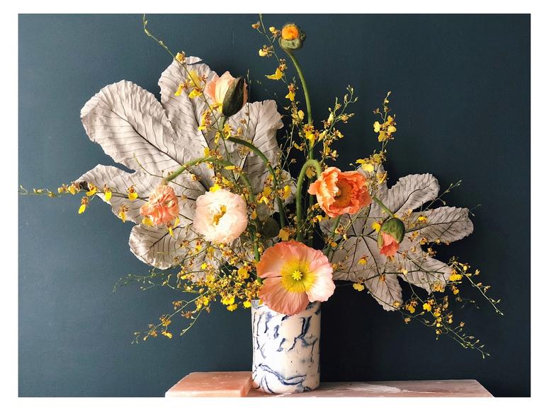 A wild looking bouquet of orange flowers on a blue background.