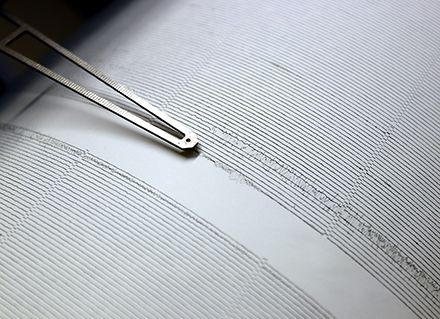 A seismograph needle drawing a black line across white paper.