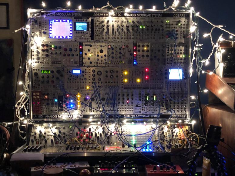 A large analog synthesizer covered in Christmas lights.