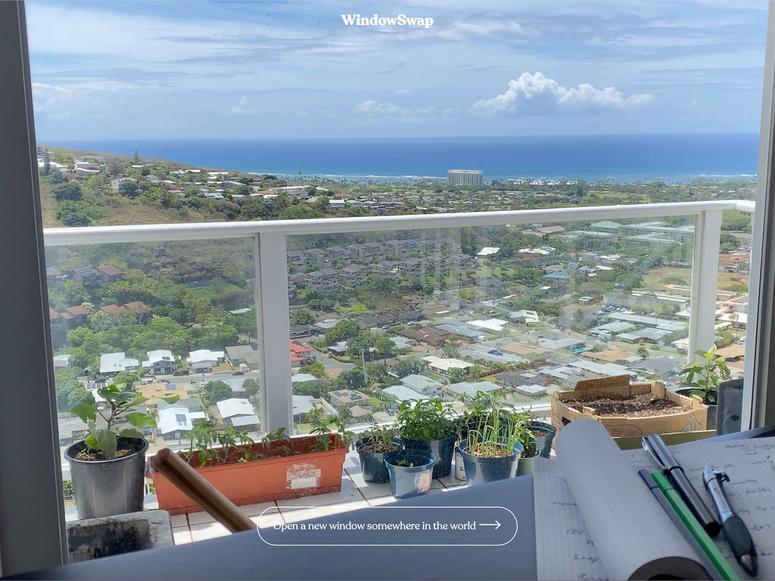 A view from a window looking out onto a neighborhood and sea beyond