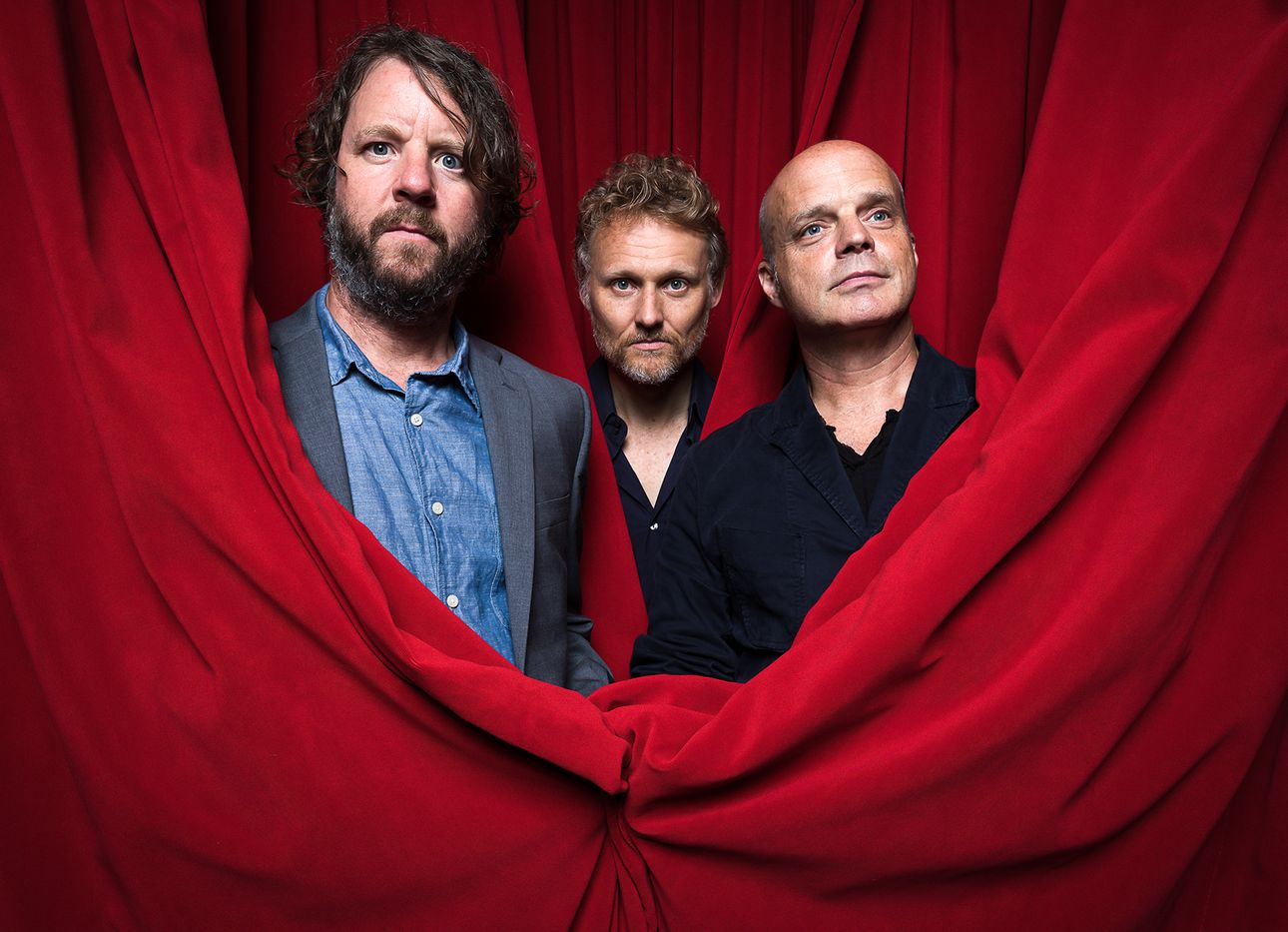 Martin, Wood, and Medeski in red theater curtains.