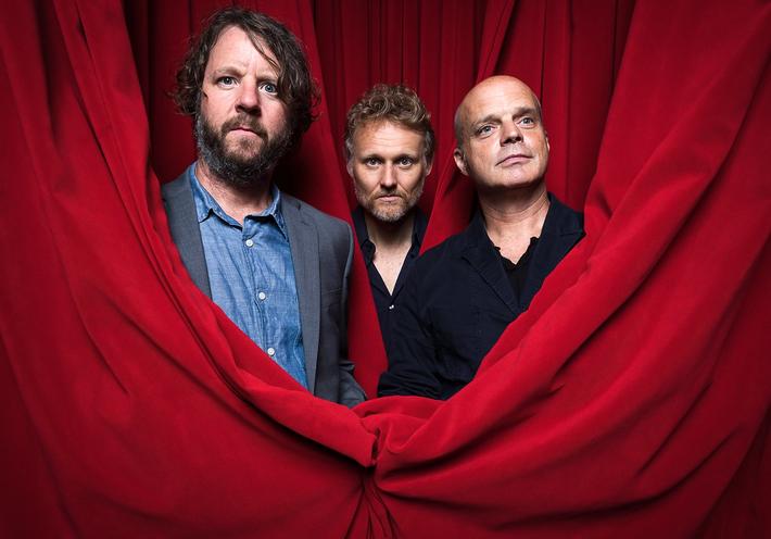 Martin, Wood, and Medeski in red theater curtains.