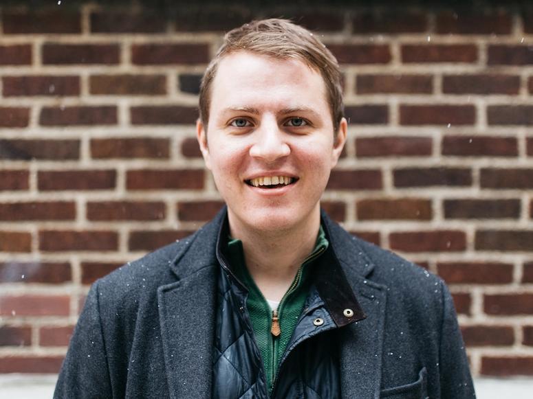 Matt Jozwiak in light snow in front of a brick wall.