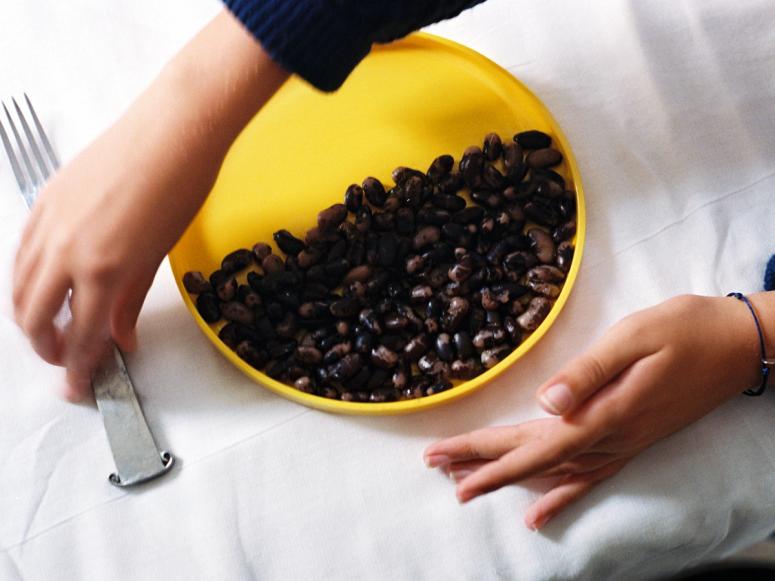 A yellow plate half filled with black beans.