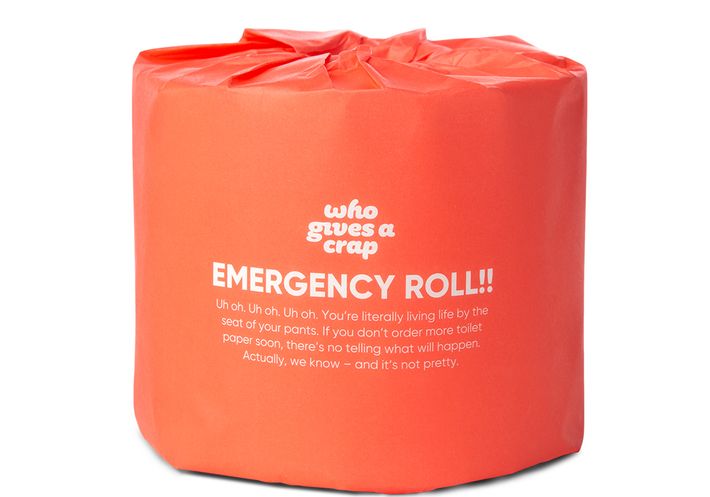 A roll of Who Gives a Crap "Emergency Roll!!" toilet paper in orange wrapping.