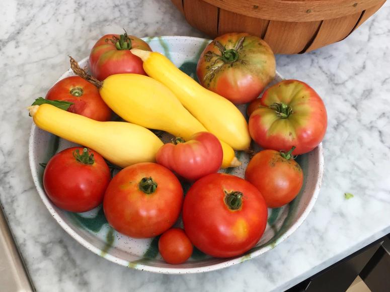 A bowl of yellow squash and tomatoes.