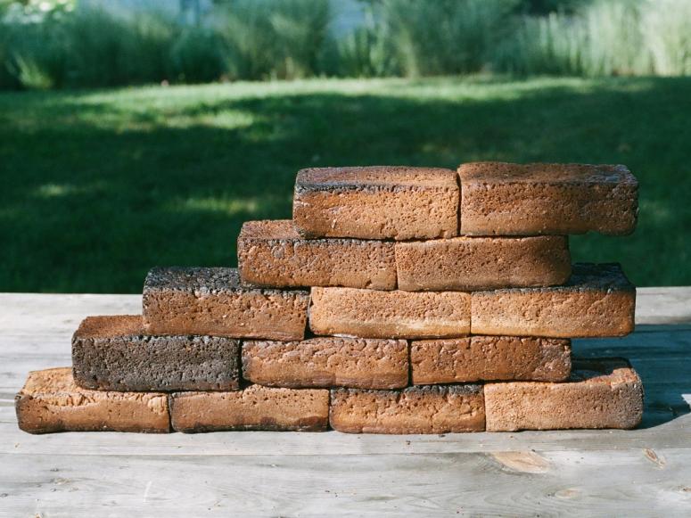 A stack of brick-like bread loaves with a green lawn in the background.