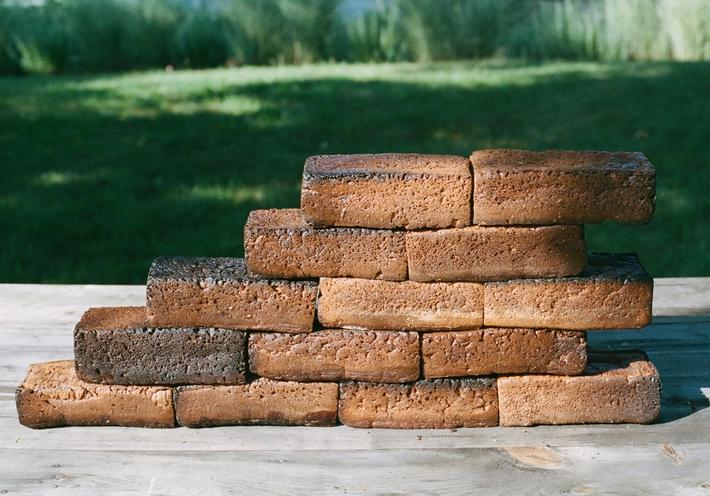 A stack of brick-like bread loaves with a green lawn in the background.