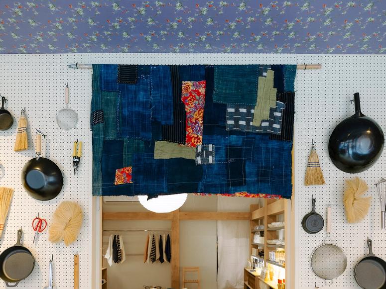 The interior of Beverly's pop-up, with a large indigo textile and cookware hanging on a white wall.