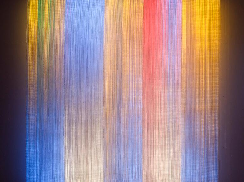 A textile in bright streaks of gold, blue, and red.