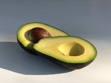 A split avocado in bright, moody lighting.