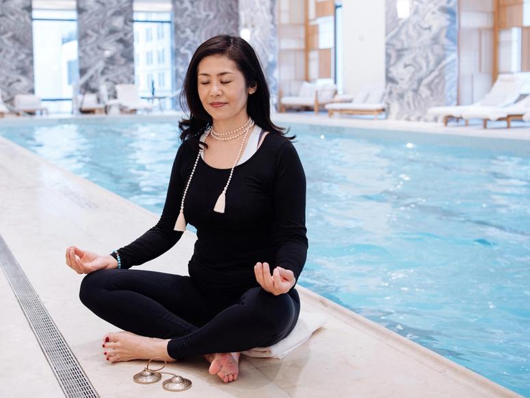Snow Shimazu meditating next to a hotel pool.