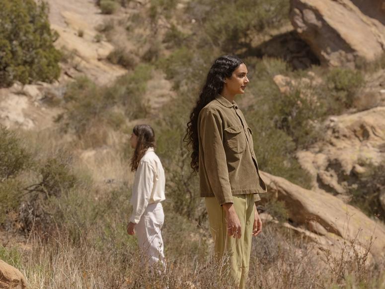 Junaco's two members facing opposite directions while standing in desert foothills.